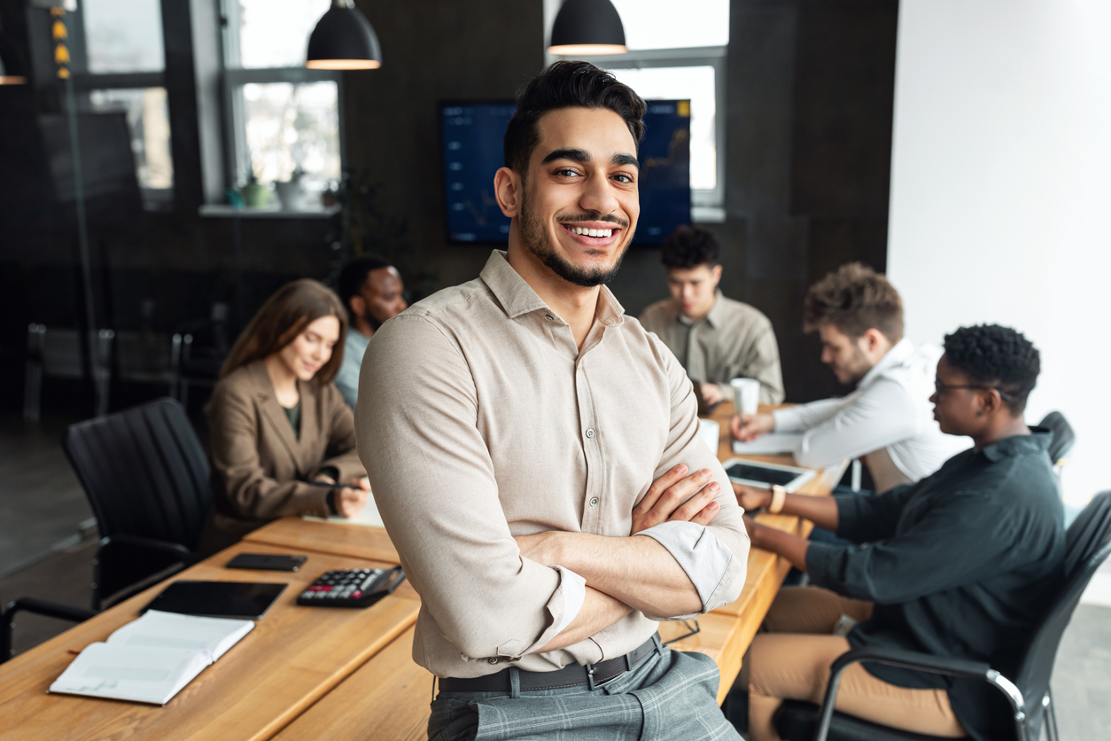 Homem adulto de pé na frente de uma mesa com um grupo de pessoas.