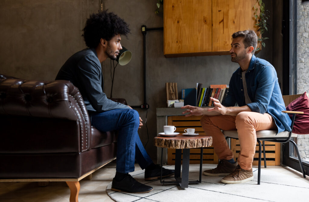 Dois homens conversando como se estivessem dando e recebendo feedbacks é um exemplo de inteligência emocional.